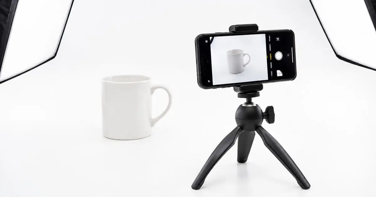 White mug on a white backdrop photographed with a phone on a tripod